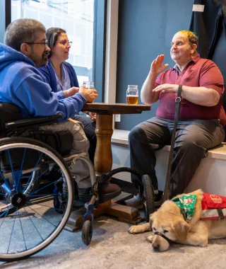 Three people sitting at a cafe with service dog
