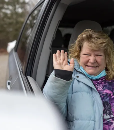 Woman waving from the passenger seat of a truck